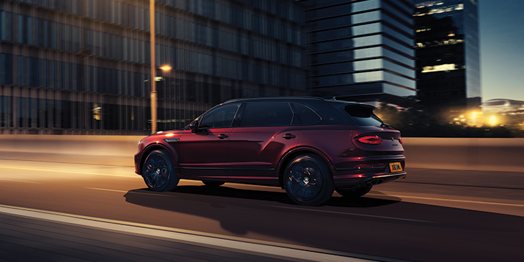 Bentley St Peter Bentley Bentayga Extended Wheelbase Mulliner SUV in Cricket Ball red paint driving dynamically in city at night