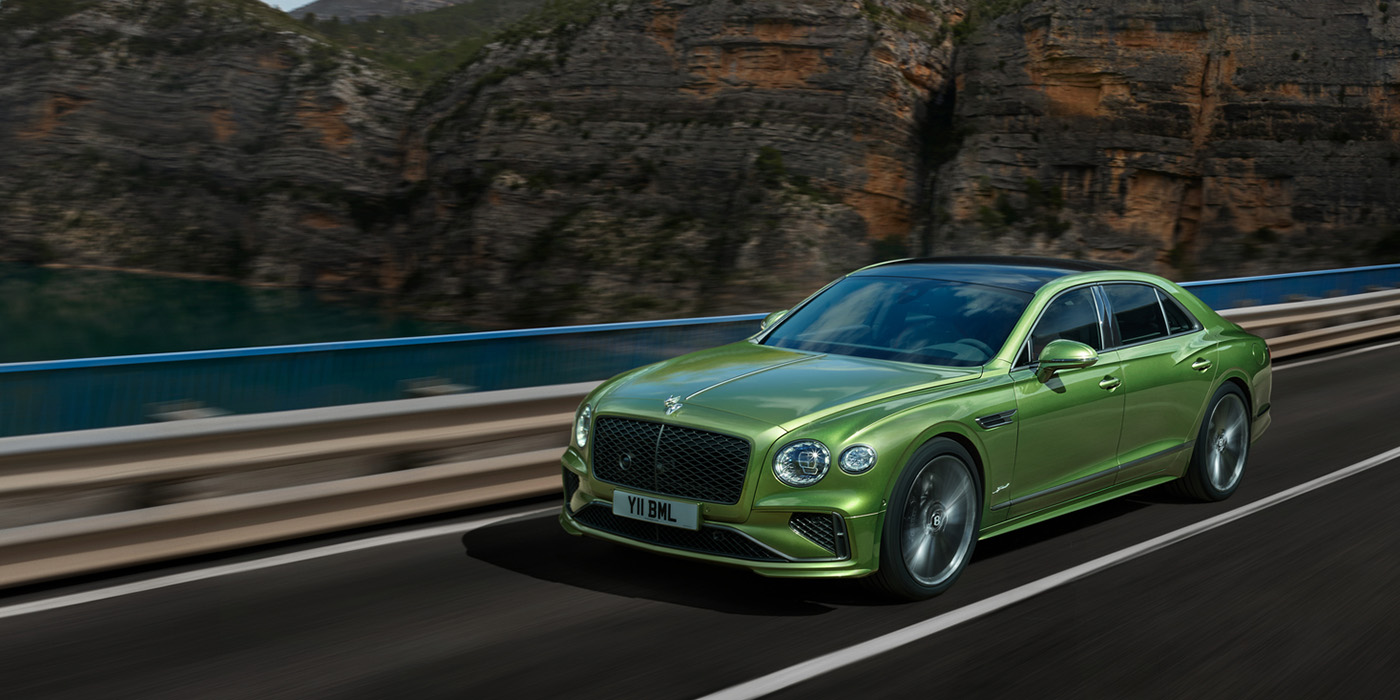 Bentley St Peter Bentley New Flying Spur Speed v8 hybrid sedan driving dynamically on a mountain road in Tourmaline Green paint