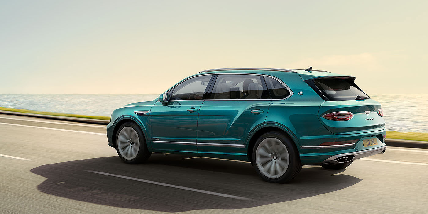 Bentley St Peter Bentley Bentayga Extended Wheelbase Azure luxury SUV rear three quarter in Topaz Blue by Mulliner paint, driving on an ocean road.