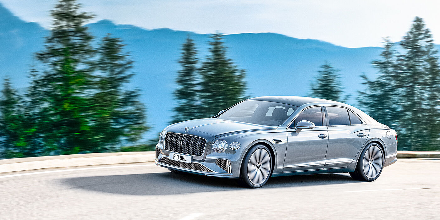 Bentley St Peter New Bentley Flying Spur sedan side view in Silverlake paint with ten spoke wheels and chrome matrix grille driving dynamically on a mountain road