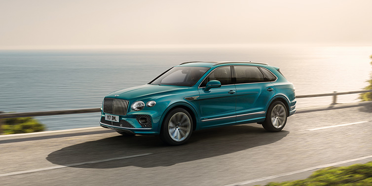 Bentley St Peter Bentley Bentayga Extended Wheelbase Azure SUV in Topaz blue paint driving dynamically by the ocean